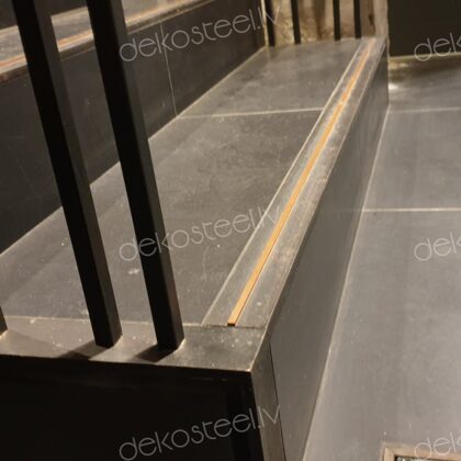 Metāla kāpņu apdare ar vara elementiem uz betona pakāpieniem.